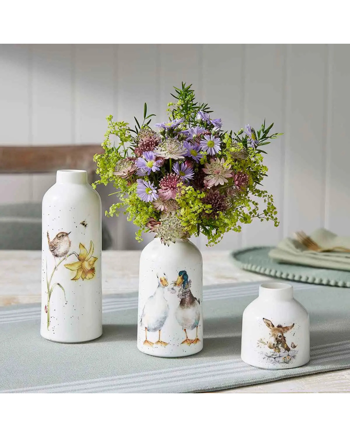 3er Set Blumenvasen von Wrendale Designs mit Vogel, Enten und Esel Motiv. Die 3 unterschiedlich großen Vasen liegen auf einem dekorierten simpel gedeckten Holztisch. Die mittelgroße Entenvase ist mit Blumen gefüllt.
