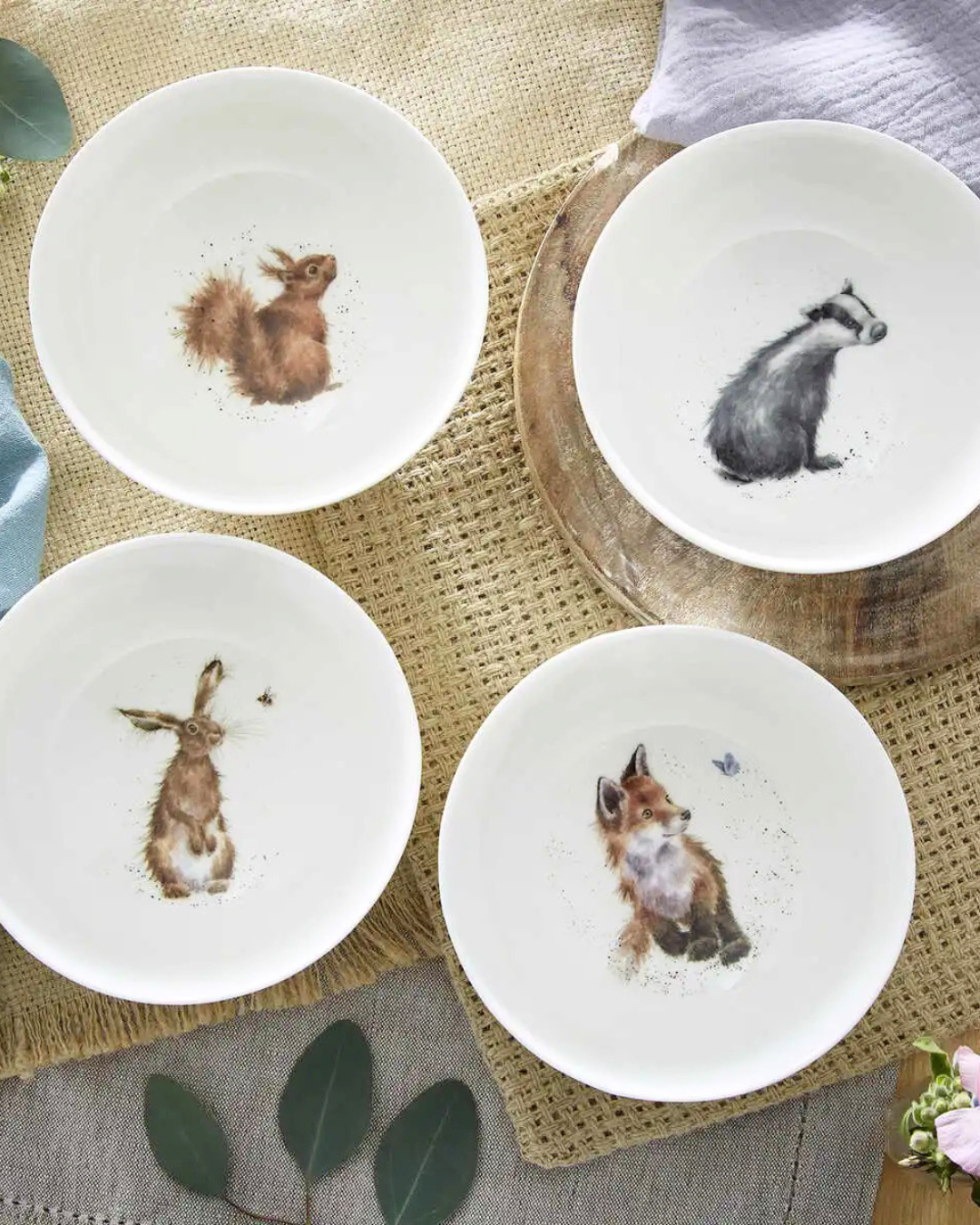 4 verschiedene "Royal Worchester" Schüsseln mit Fuchs, Hase, Eichhörnchen und Dachs Motiv von Wrendale Designs liegen auf einem gedeckten Tisch. 