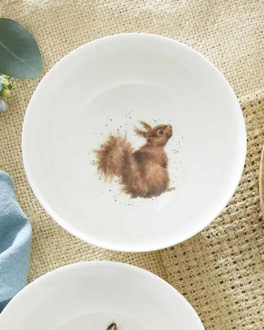 Eichhörnchen Bowl "Royal Worchester" von Wrendale Designs auf einem beeckten Tisch. Der Teller selbst ist weiß. Das Motiv zeigt ein Eichhörnchen welches neugierig nach hinten in die Kamera schaut. 
