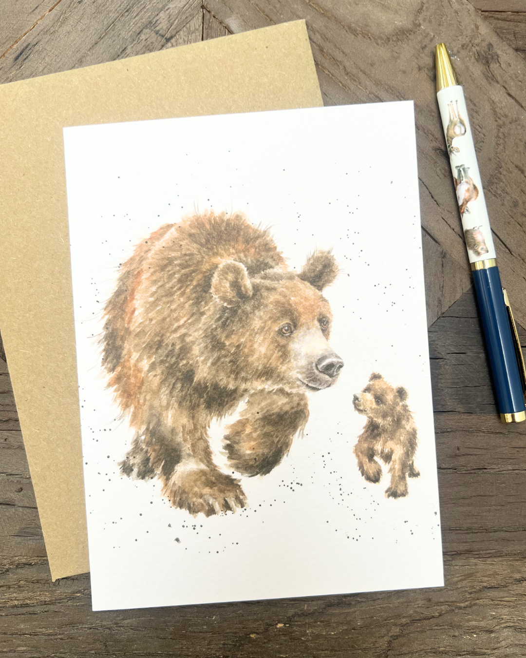 Auf einem Holztisch dekorierte Bären Grußkarte Follow me von Wrendale Designs mit einem Kugelschreiber.
