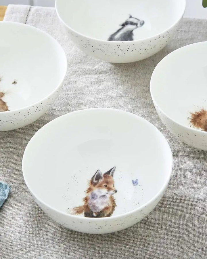 Weiße Fuchs Schüssel "Royal Worchester" aus Porzellan von Wrendale Designs vor weißen Hintergrund. Das Motiv zeigt einen Fuchs welcher glücklich einen Schmetterling anschaut. Im Bild sind noch 3 andere Schüsseln mit den Motiven Dachs, Eichhörnchen und Hase teilweise zu sehen.