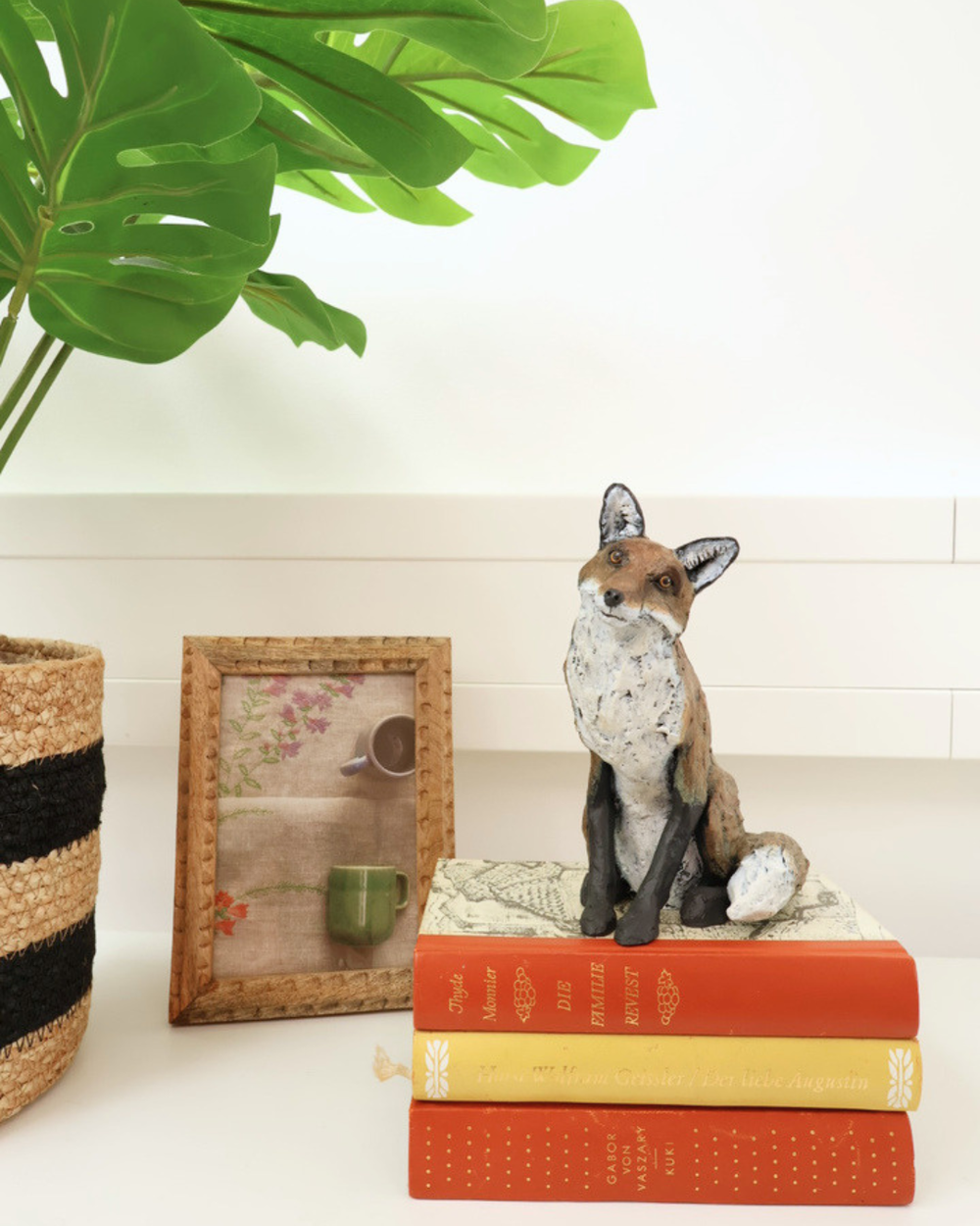 Fuchs Statue "Autumn" von Wrendale Designs dekoriert auf 3 Büchern welche auf einem weißen Tisch liegen. daneben ist ein Bild und eine Pflanze.