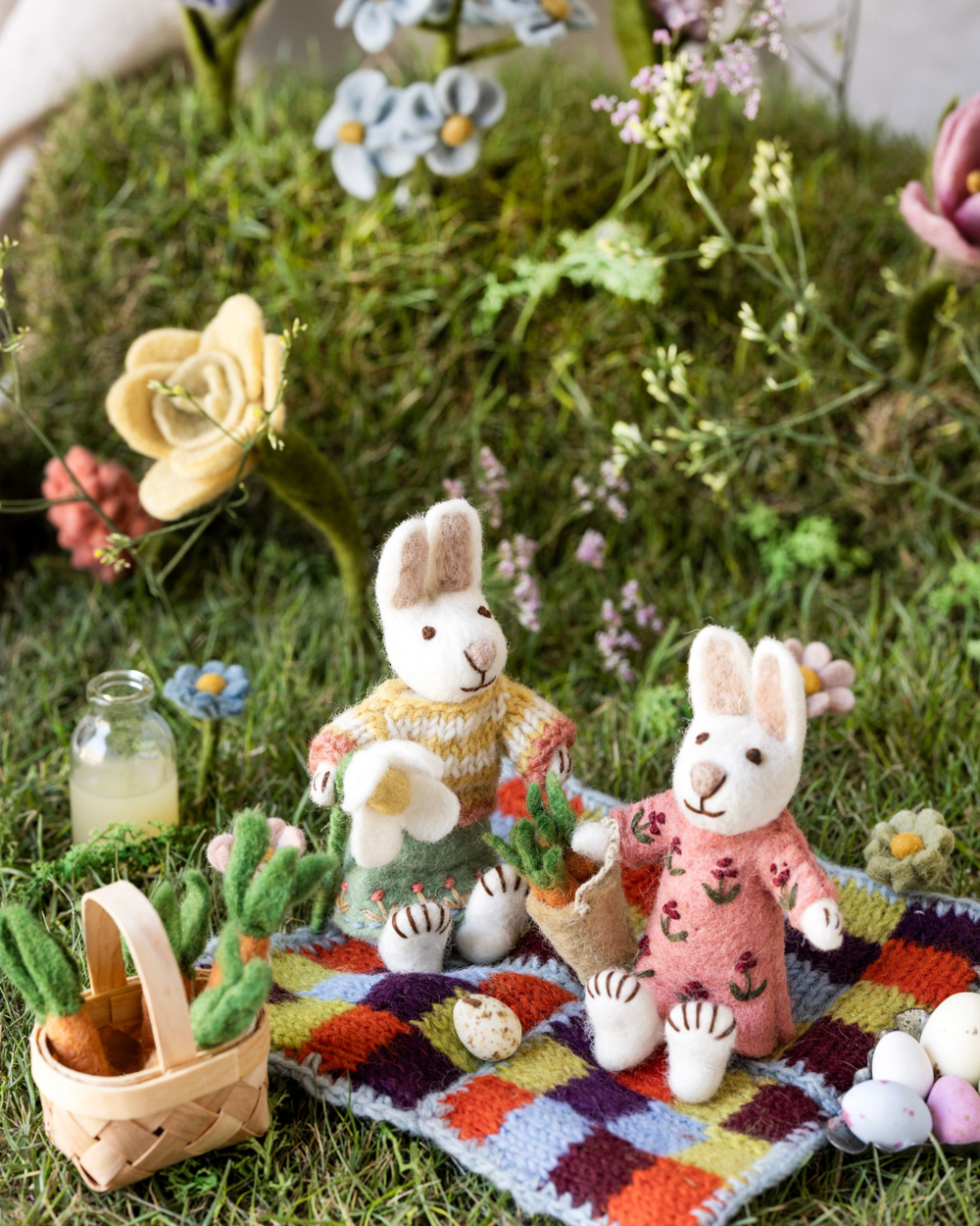 Filzhasen von Gry & Sif mit Karotten dekorativ in einer frühlingshaften Wiesenlandschaft zwischen Filzblumen und Osterdekoration arrangiert.