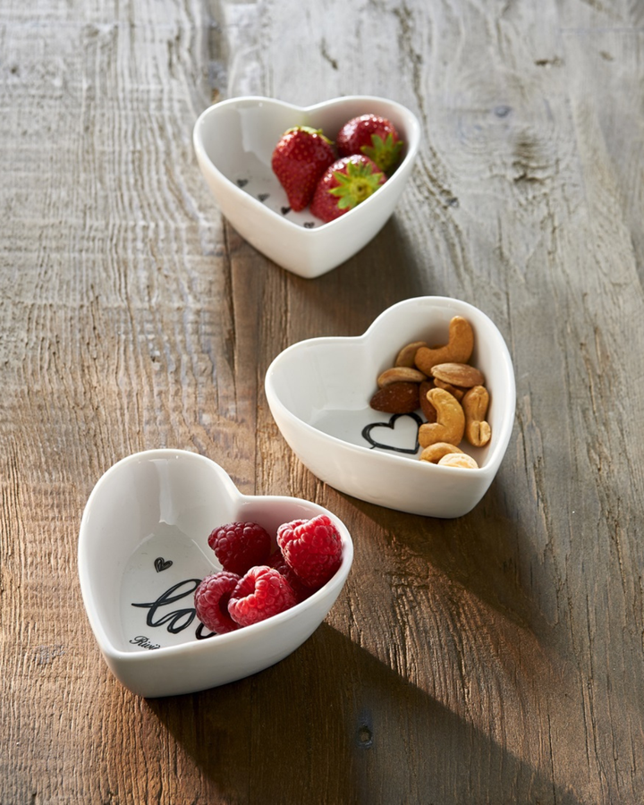 Drei Herz-Schälchen „Lovely Heart Bowls“ von Rivièra Maison auf rustikalem Holztisch, gefüllt mit Erdbeeren, Himbeeren und Nüssen.
