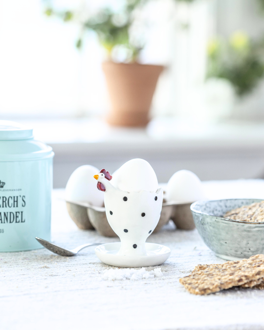 Weißer Eierbecher in Hühnerform von Nääsgränsgården mit Ei auf gedecktem Frühstückstisch