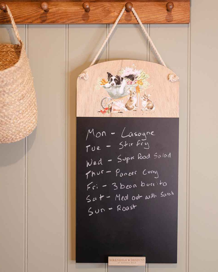 Dekorierte Szene mit der Hunde-Kreidetafel „Sleeping on the Job“ von Wrendale Designs, beschriftet und an einer Wand im Wohnbereich aufgehängt.