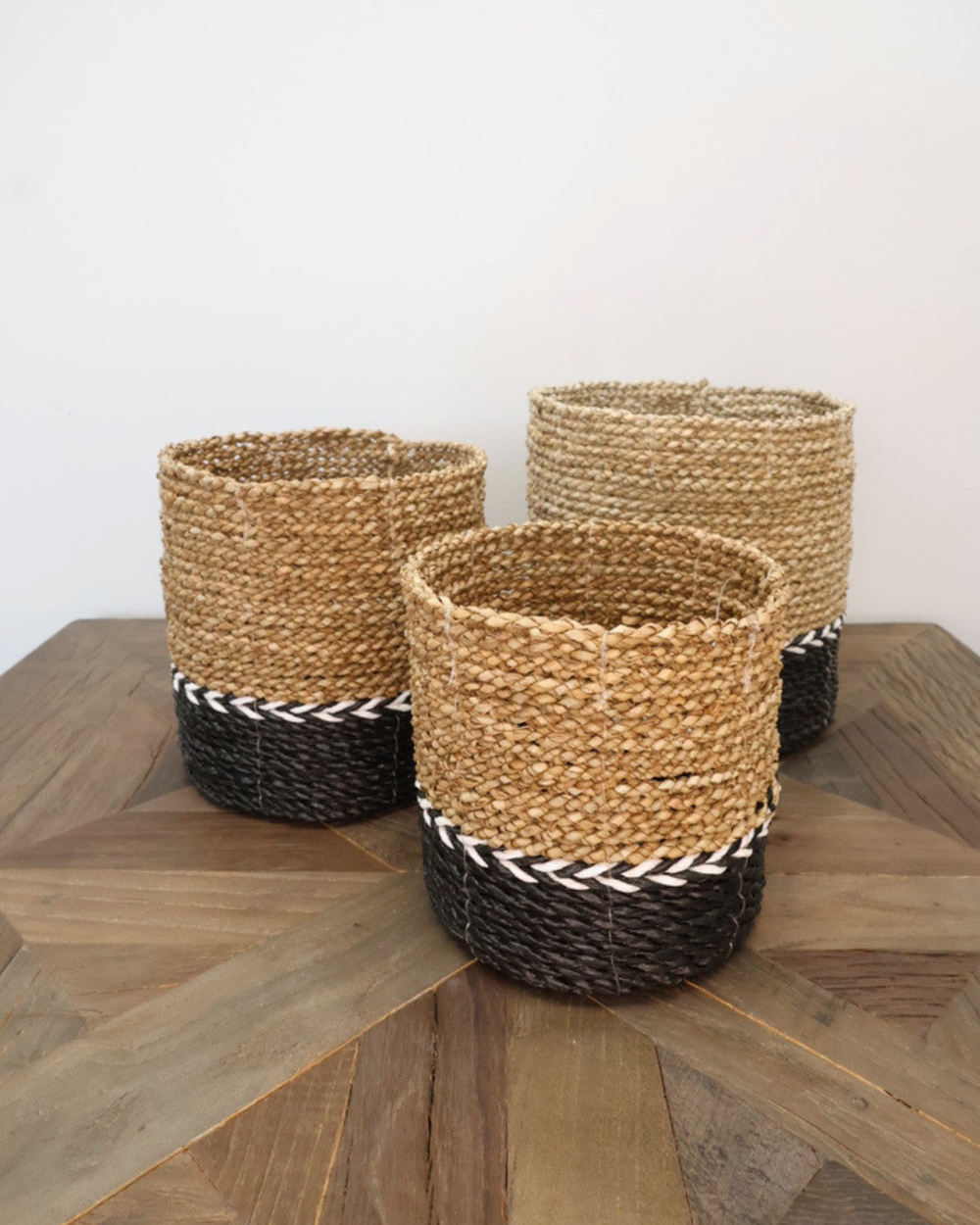 Drei Körbe Schwarz/Weiß von Eigen en Anders in unterschiedlichen Größen, geflochten aus Naturmaterialien mit markanten schwarzen und weißen Streifen, angeordnet auf hellem Holztisch.