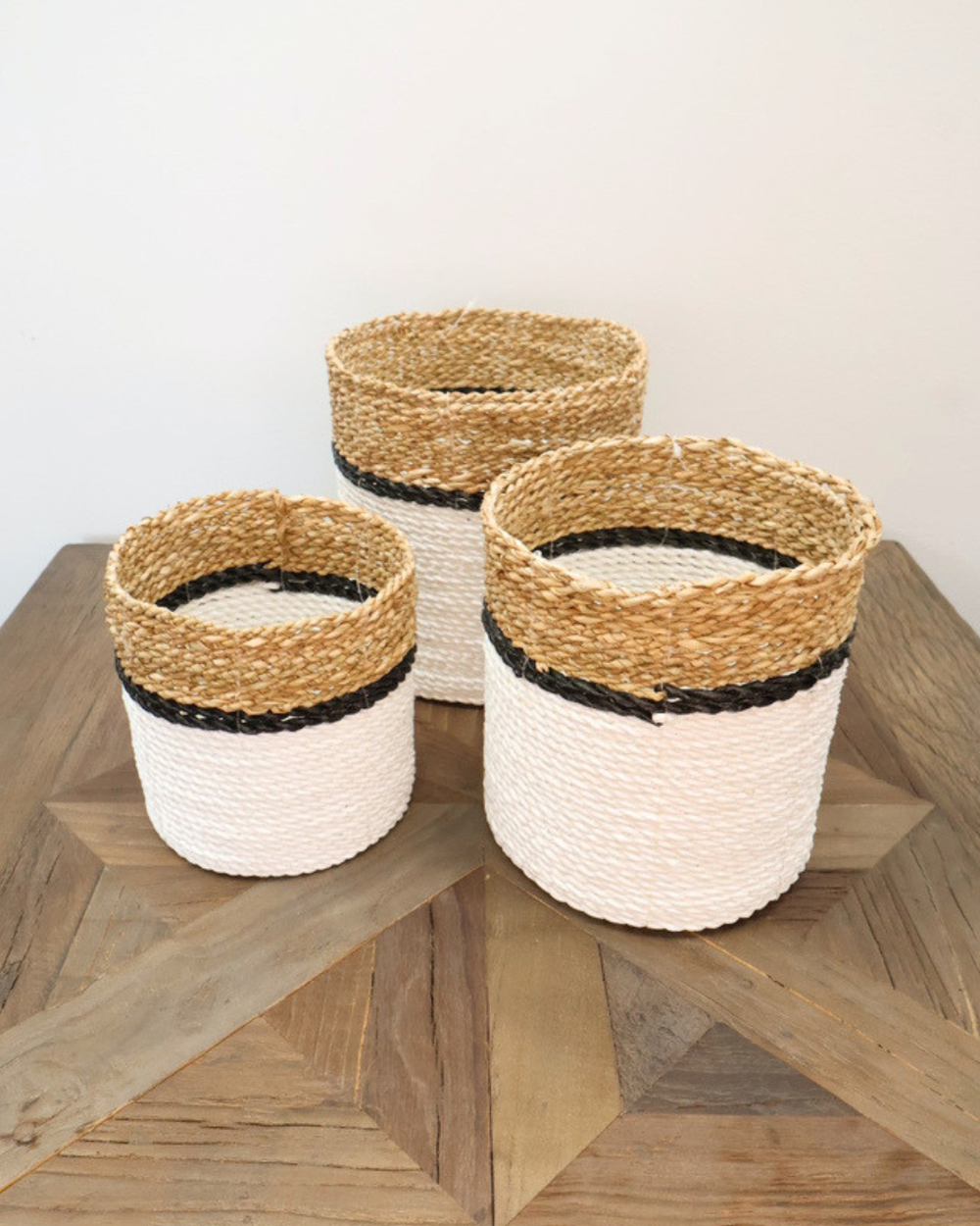 Drei Körbe Weiß/Schwarz von Eigen en Anders in unterschiedlichen Größen, geflochten aus Naturmaterialien mit markanten weißen und schwarzen Streifen, angeordnet auf hellem Holztisch.