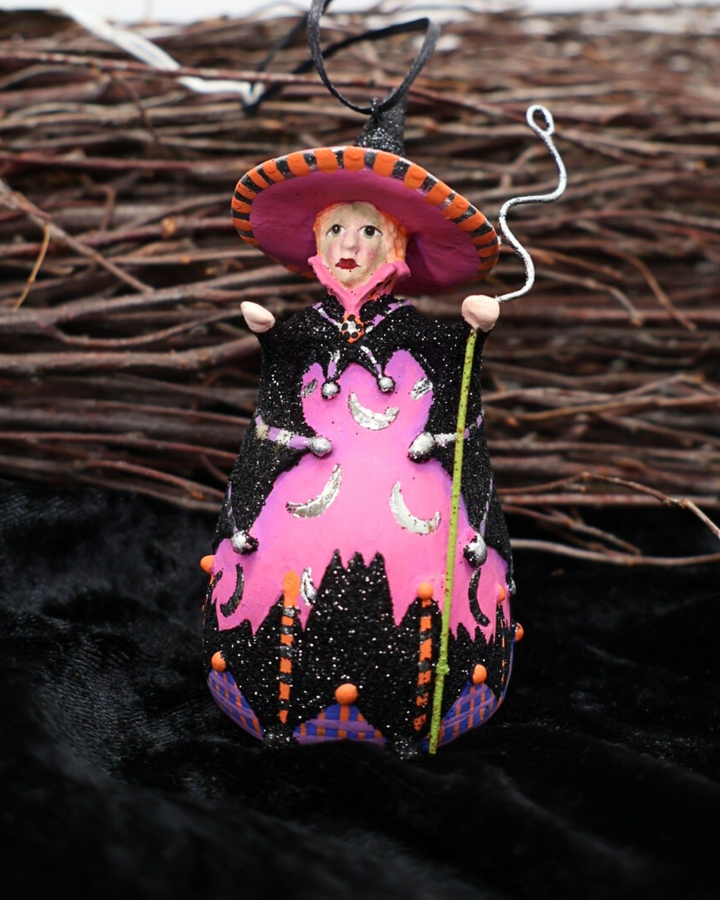 Dekorierte Krinkle Hexen Figur „Mini Bat Moon Witch“ von Patience Brewster als Halloween-Deko vor einem Reisigbesen auf einem schwarzen Samttuch.