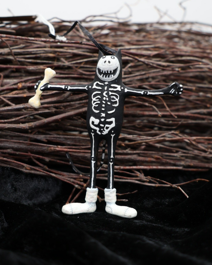 Krinkle Katze Mini Boney Cat von Patience Brewster für Halloween vor einem Reisigbesen und auf schwarzem Samt dekoriert.