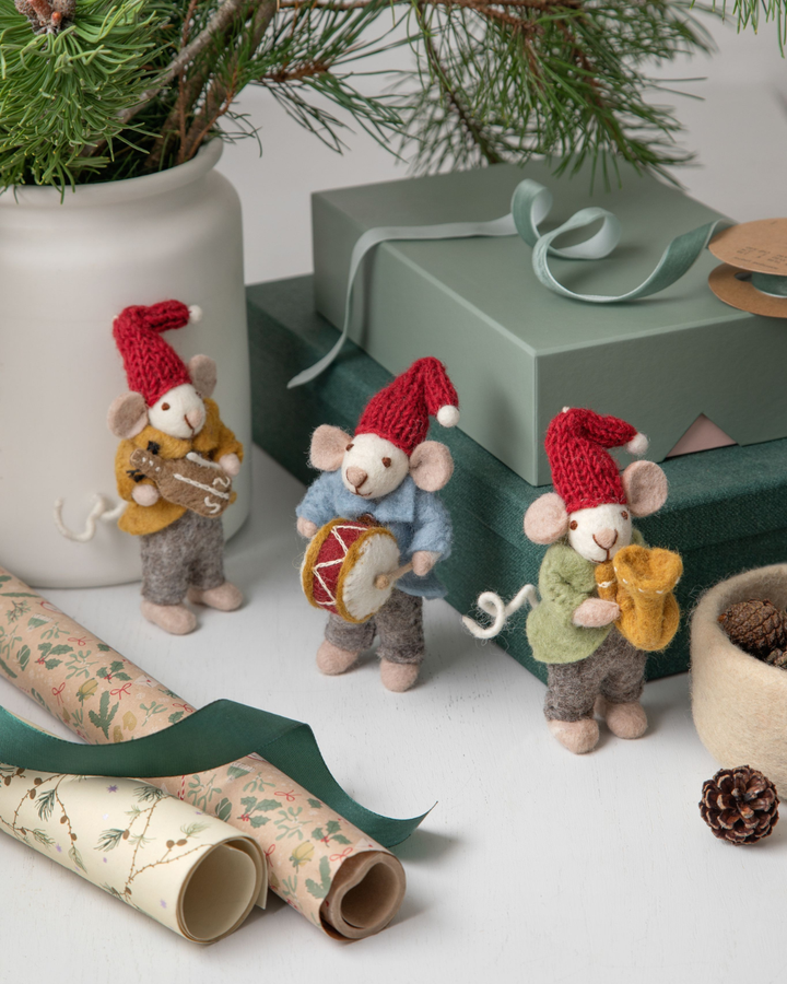 Drei Filzmusikanten-Mäuse in winterlicher Deko mit Geschenken und Tannenzweig.