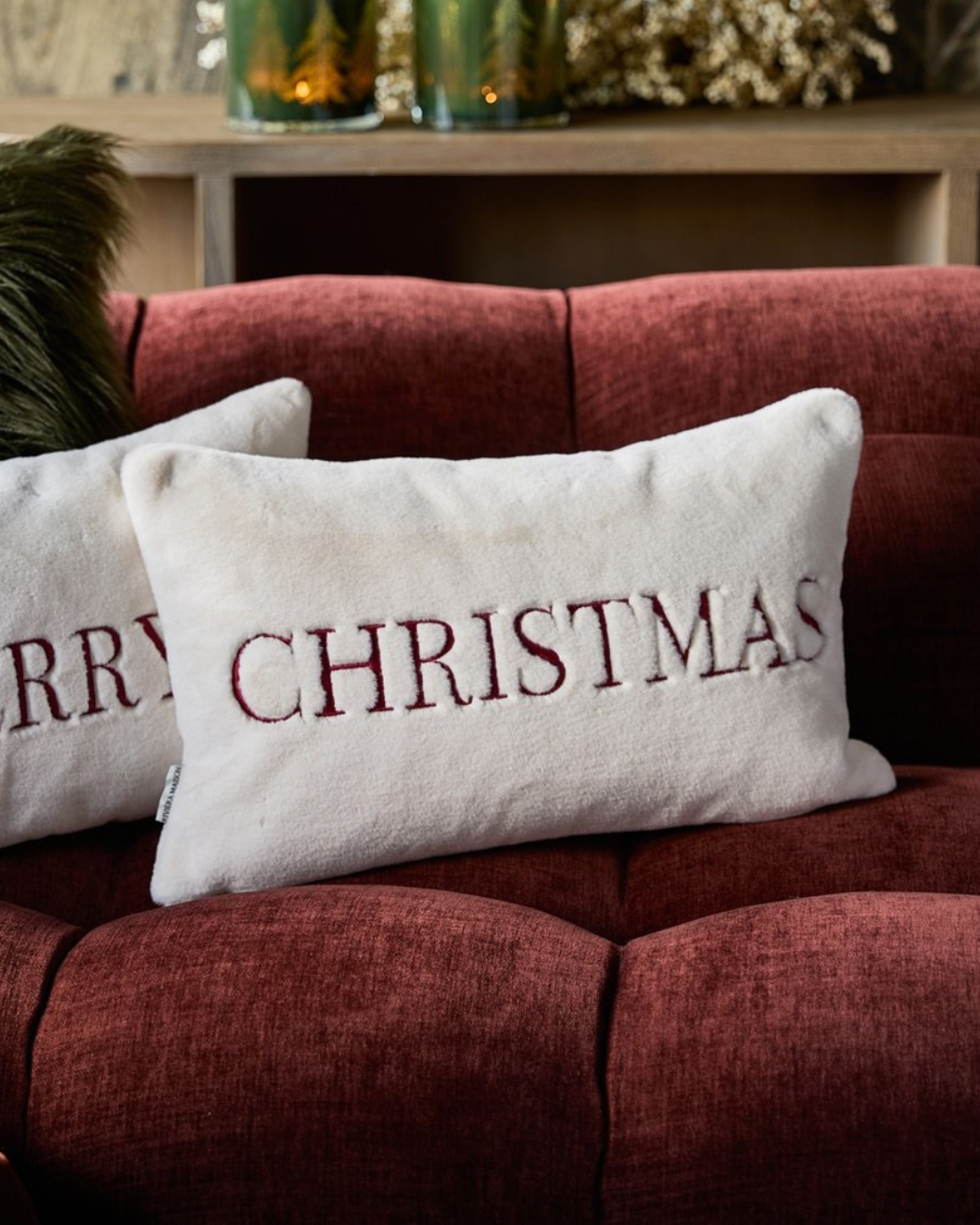 Christmas-Kissen dekoriert auf rotem Sofa mit weihnachtlichem Ambiente