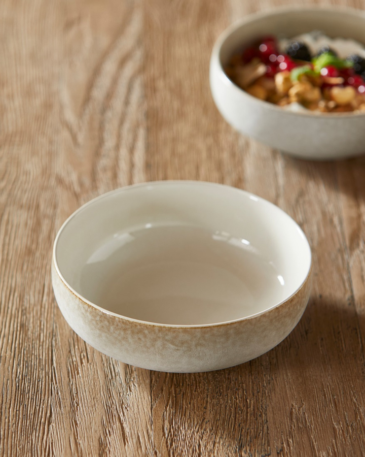 Die Sevran-Bowl von Rivièra Maison mit Müsli, Nüssen und Beeren auf einem Holztisch.