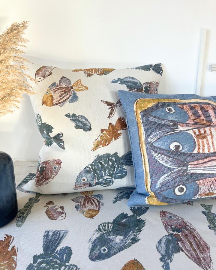 Auf einem Tisch dekoriertes Glup Kissen mit mehreren Fischen und das Scatola Kissen mit Sardinen als Motiv von Sander.