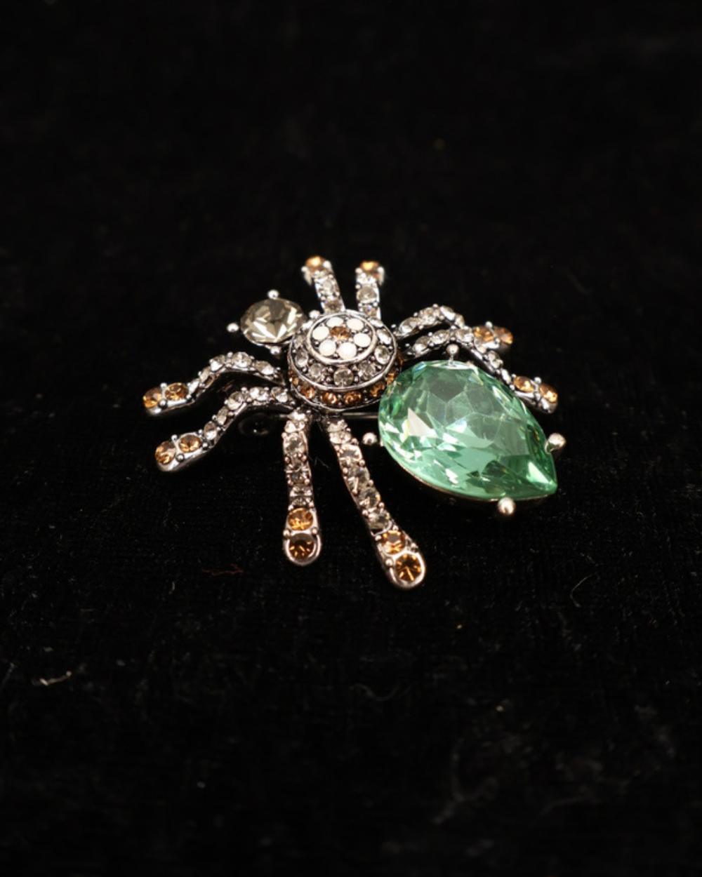 Mit Glitzersteinen verzierte Vorderseite der Spinnen Brosche "Elegant Spider" von Giuno auf schwarzer leicht glitzernder Decke.