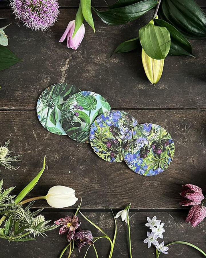 4er Set "Anne Just" Untersetzer von Koustrup & co mit Blumenmotiv auf dunklen Holztisch. Der Tisch ist verziert mit Blumen.