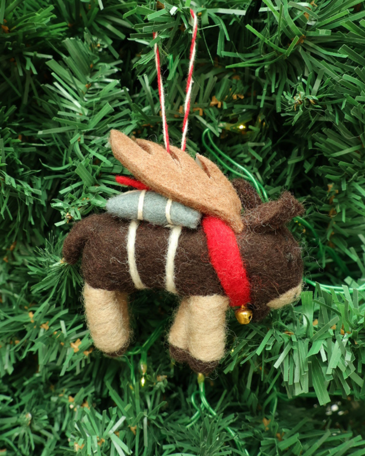 Dekorierter Elch Weihnachts-Filzanhänger  "Elton" von Grace & Gloria. hängt am Tannenbaum. Der Elch hat Flügel und trägt eine Glocke um sein Hals.