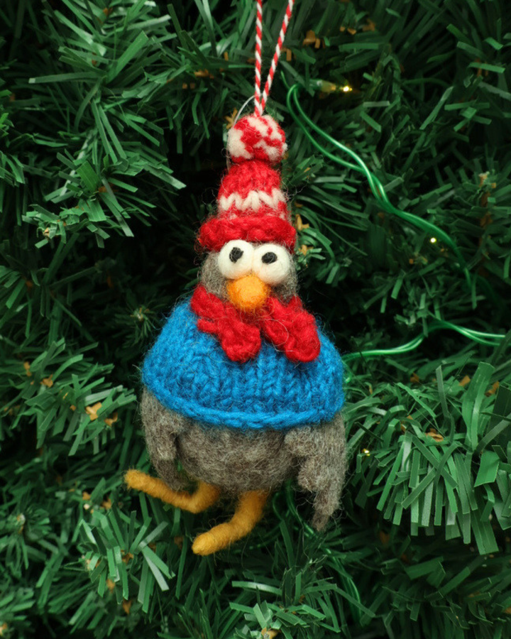 Dekorierter Weihnachts-Hahn- Filzanhänger "Willi" von Grace und Gloria. Der süße graue Hahn Anhänger trägt eine rot/weiß gestreifte Mütze und einen blauen Schal. er Hahn hängt an einem Weihnachtsbaum.
