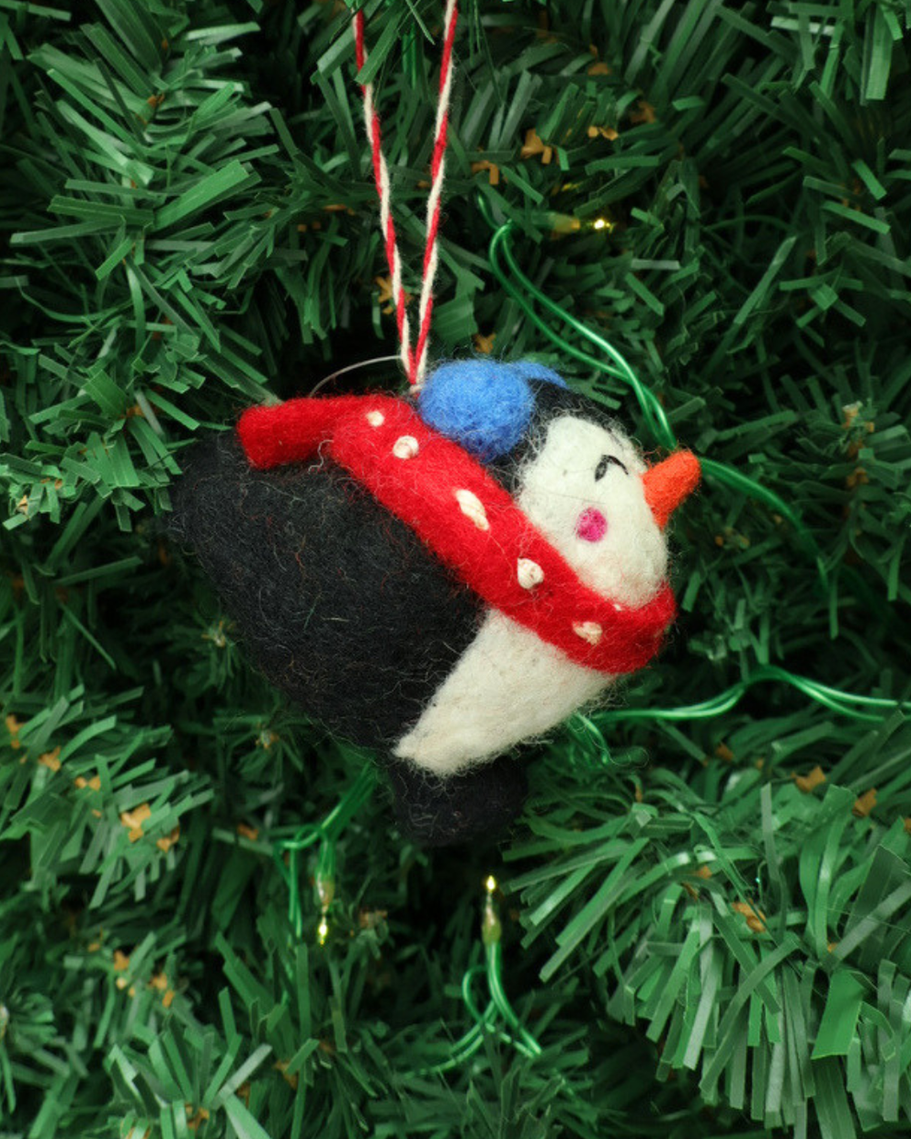 Dekorierter Weihnachts-Pinguin Filzanhänger"Pia" von Grace & Gloria. Der Süße Pinguin Ahnänger ist schwarz weiß und trägt einen roten Schal mit weißen Pünktchen Schal.