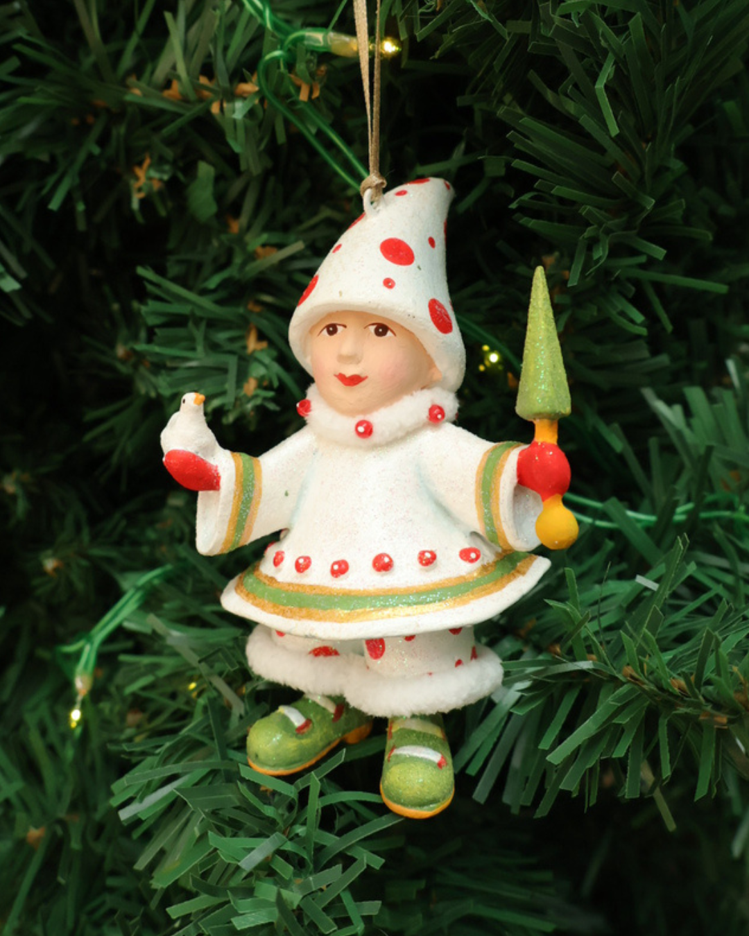 "Blitzens Elf" Krinkles vor weißen Hintergrund. Zu sehen ist ein größtenteils weiß bekleideter Elf mit roten Pünktchen. In den Händen hält es jeweils einen kleinen Vogel und ein kleinen Tannenbaum Stab.