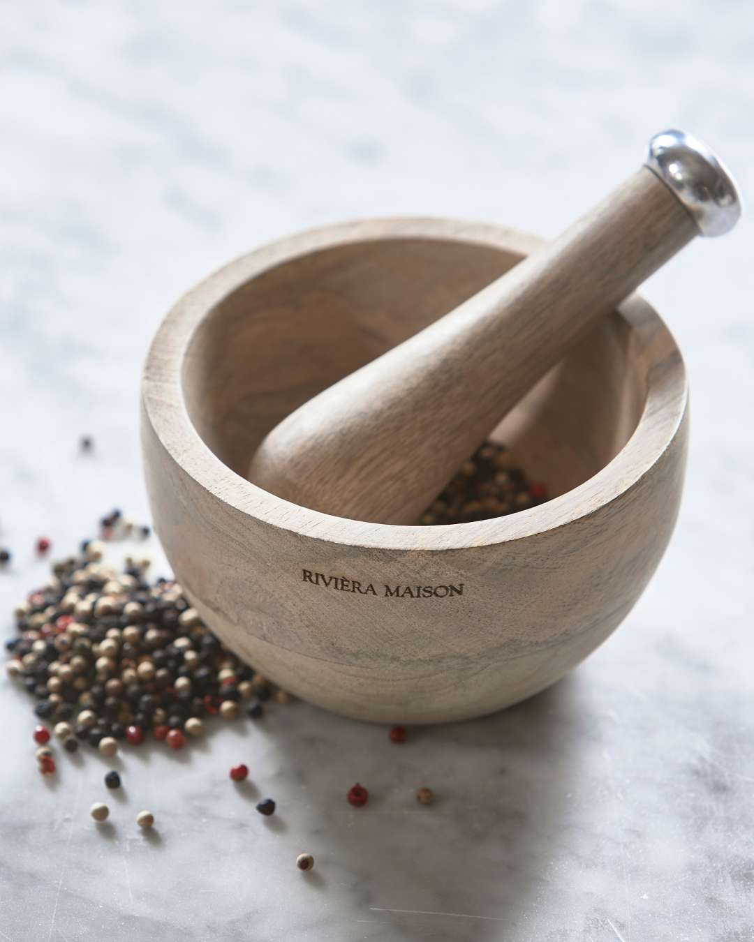 RM Mortar & Pestle von Rivièra Maison auf heller Steinoberfläche mit bunten Pfefferkörnern, dekorative Küchenszene.
