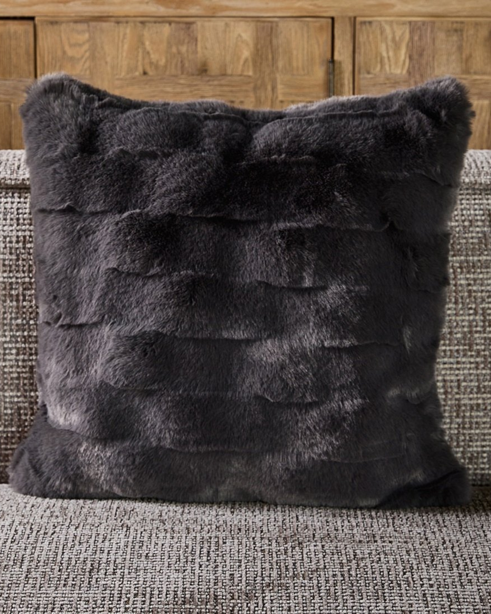 Dekorierter Romolo Faux Fur Kissenbezug auf braun-grauem Sofa.