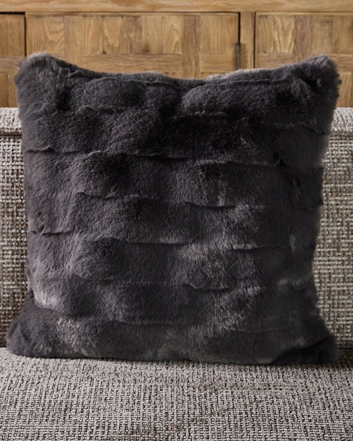 Dekorierter Romolo Faux Fur Kissenbezug auf braun-grauem Sofa.