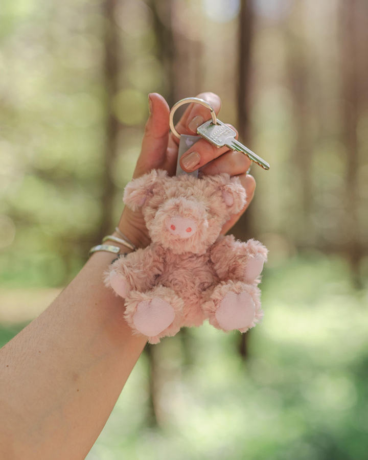 Schweine Schlüsselanhänger Vanessa von Wrendale Designs in der Hand mit Schlüsselring, flauschige Schweinefigur Nahaufnahme