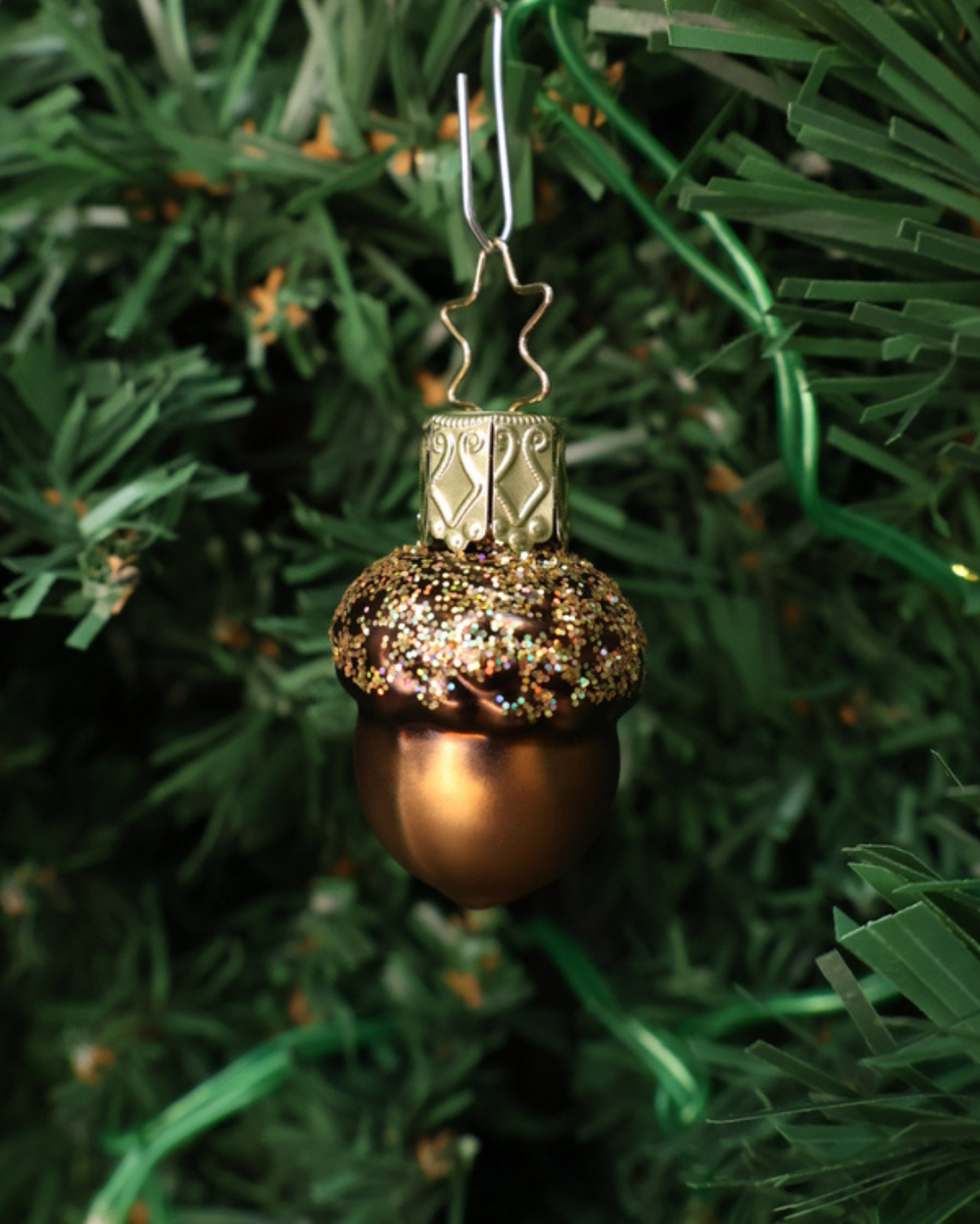 Weihnachtliches Eichel Ornament in klein von Inge Glas in einem grünen Tannenbaum hängend.