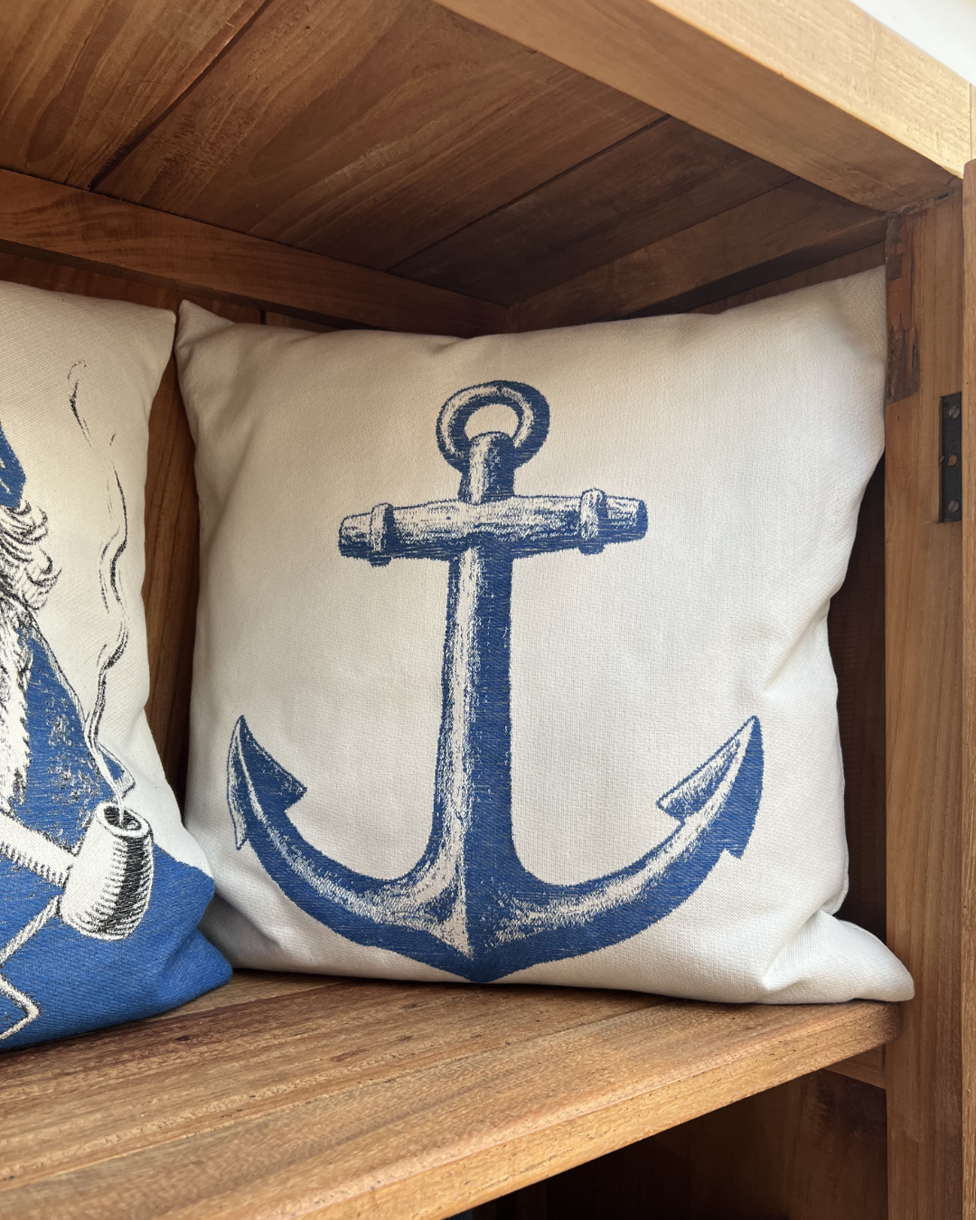 In einem braunen Schrank dekoriertes maritimes Kissen Hook von Sander mit einem Anker-Motiv.