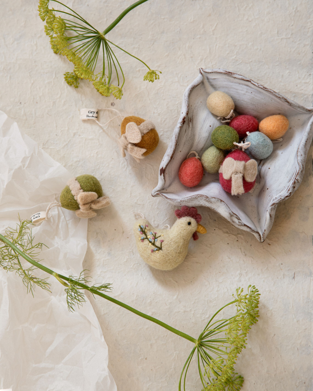 Bestickte Filzhühner von Gry & Sif neben gefilzten Ostereiern in einer dekorativen Schale arrangiert.