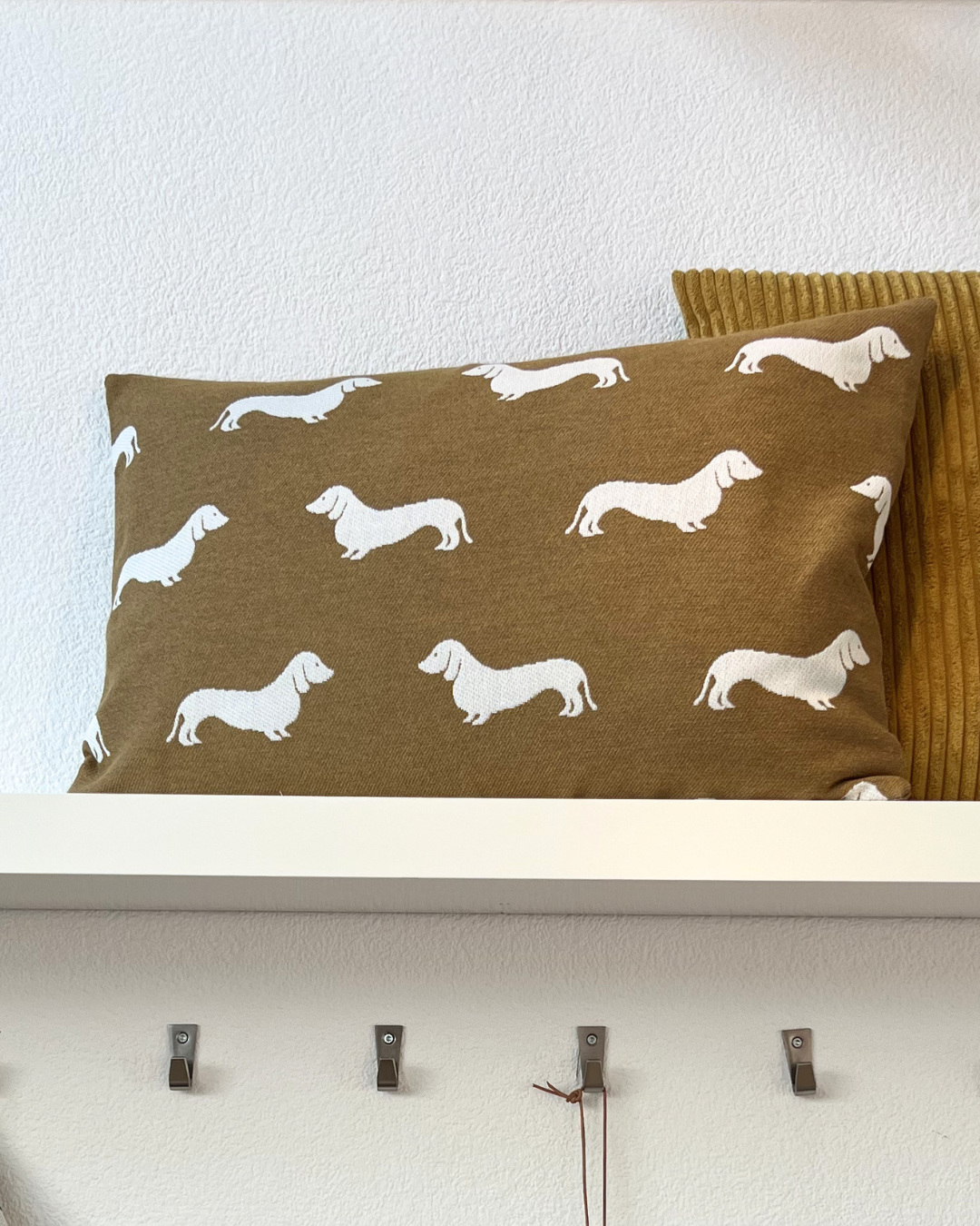 Auf diesem Kissenbezug ist ein detailreiches All-Over-Muster niedlicher weißer Dackel auf einer Safran Grundfarbe abgebildet.