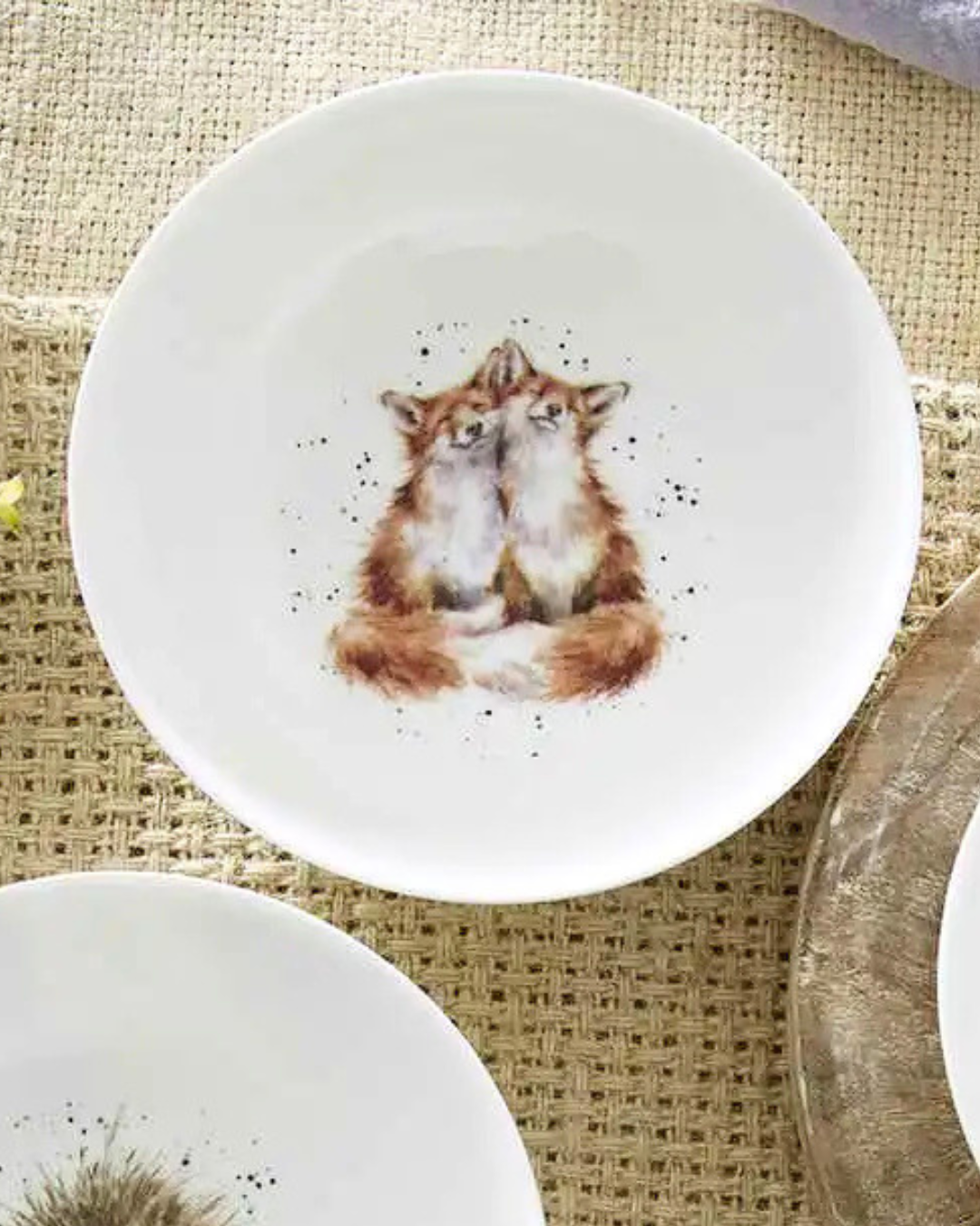 Weißes Fuchs Schüsselchen "Royal Worchester" aus Porzellan von Wrendale Designs auf bedeckten Tisch. Das Motiv zeigt 2 kuschelnde Füchse. 