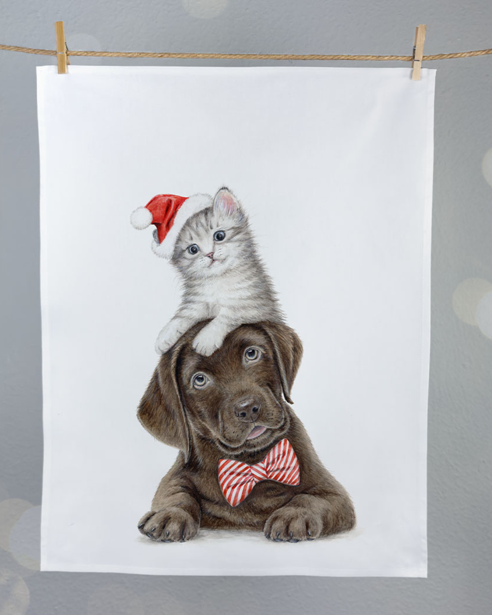 Haustier Geschirrtuch Christmas Pets von Maluu, aufgehängt an einer Leine mit weihnachtlichem Hund und Kätzchen Motiv dekoriert vor grauem Hintergrund.