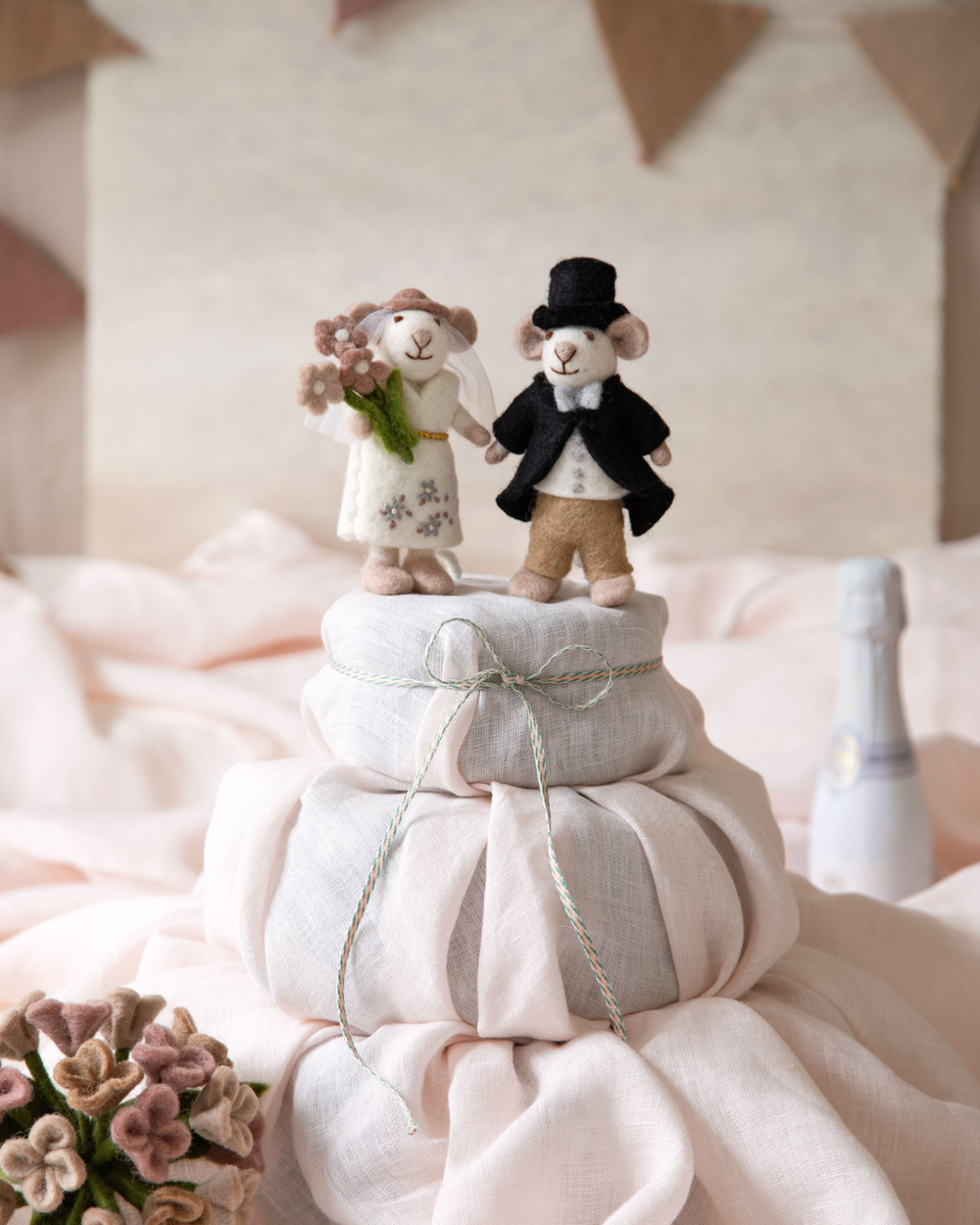 Abgebildet ist das Hochzeitspaar Maus als Filzanhänger von Gry & Sif in Weiß mit weißer Jacke und im schwarzen Anzug mit Hut. auf einem rosa Tuch.