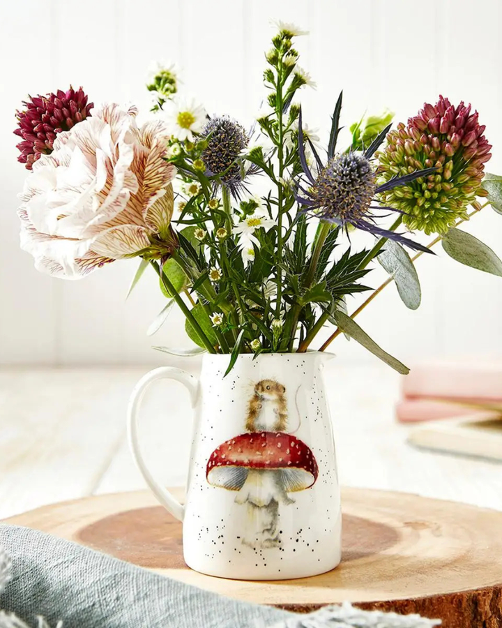 Maus Krug von Wrendale Designs gefüllt mit Blumen Auf einem Holzstamm inspirierten Tisch im Wohnzimmer. Das Motiv des Krugs ist eine niedliche Maus welche auf einem Fliegenpilz steht. 