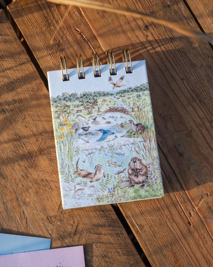 Vorderseite des Mini Notiz- und Skizzenbuchs „Riverbank“ mit detailreicher Illustration einer Flusslandschaft.