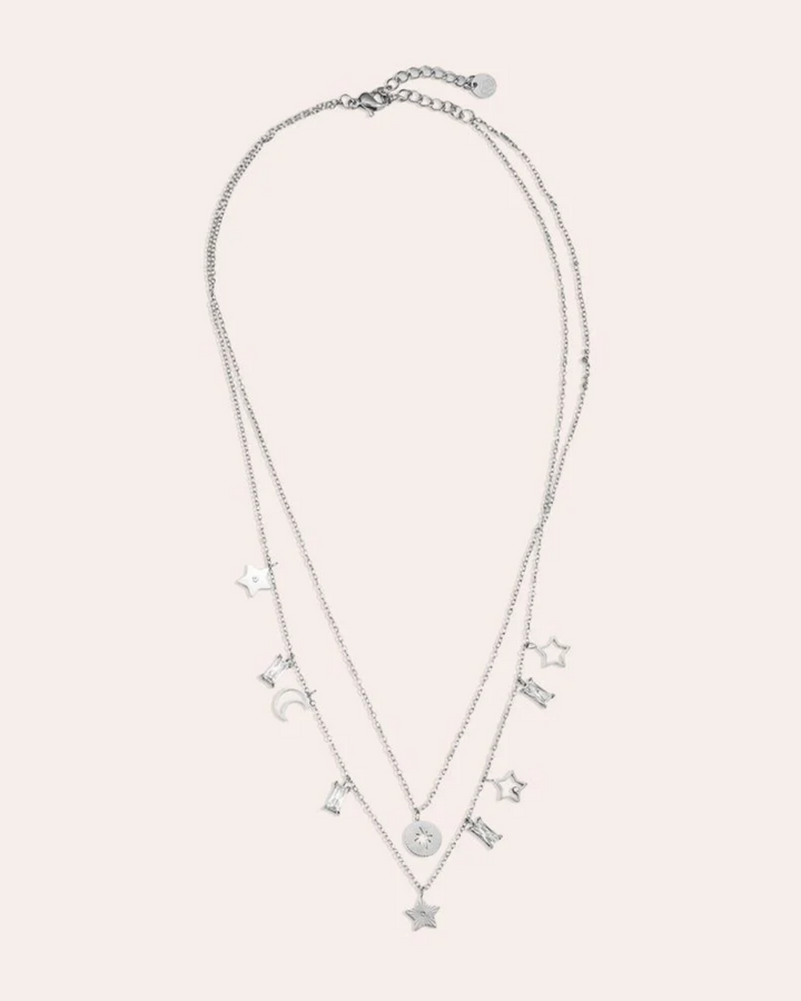 von einer Puppe getragene Doppellagige Kette mit Sternen und Mond von Dottilove in Silber. Die Kette ist größtenteils Silber mit Stern und Mond Anhängern und weißen Steinen.
