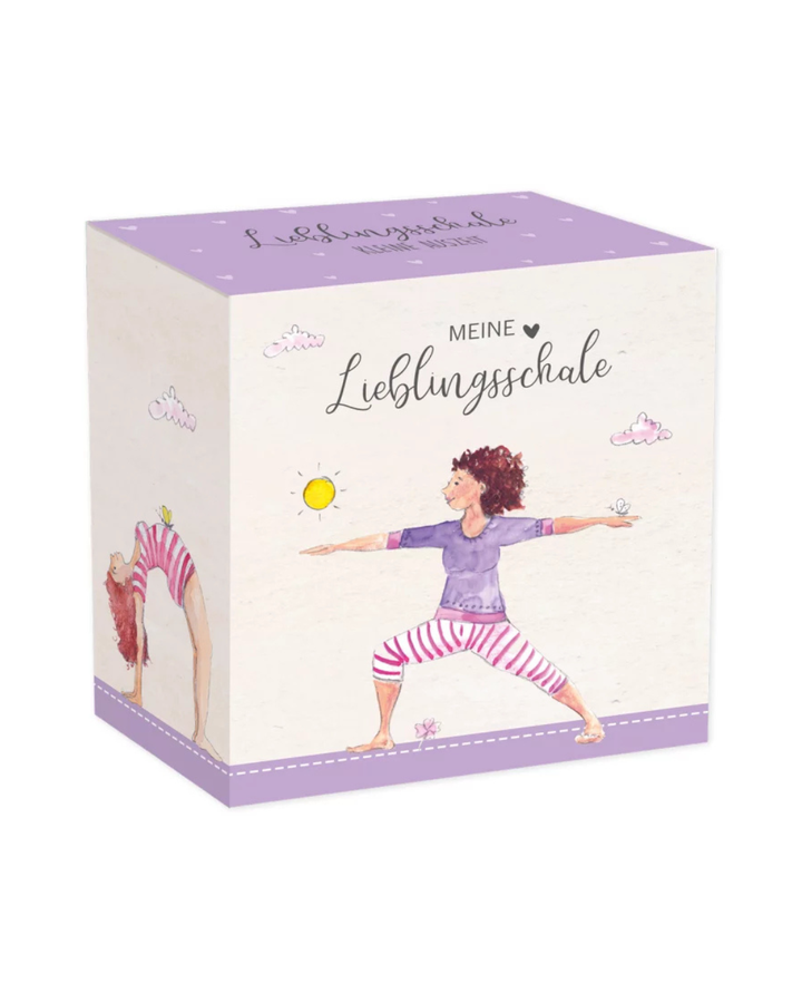 Die Verpackung der Müslischale „Kleine Auszeit“ vom Grätz Verlag. Die Schachtel ist lila mit Yoga-Motiven und der Aufschrift „Meine Lieblingsschale“.