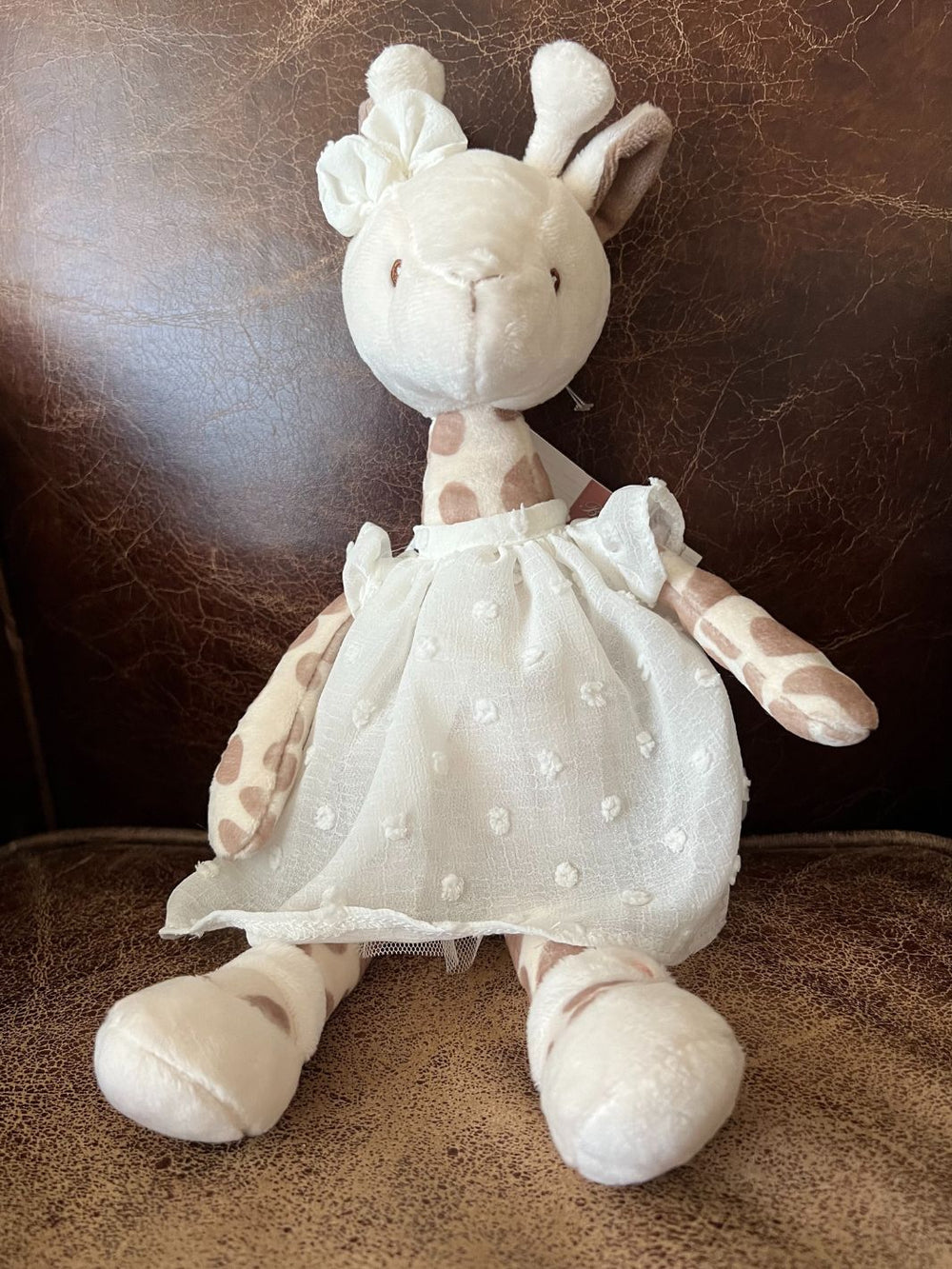 Giraffe Lucy von Bukowski sitzend auf braunem Ledersofa