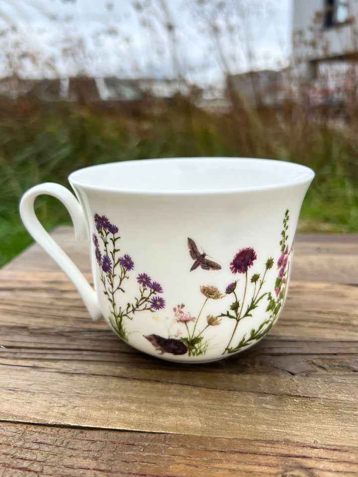 Grätz Verlag Stockrosen und Gartenbewohner auf einer Tasse aus Porzellan.