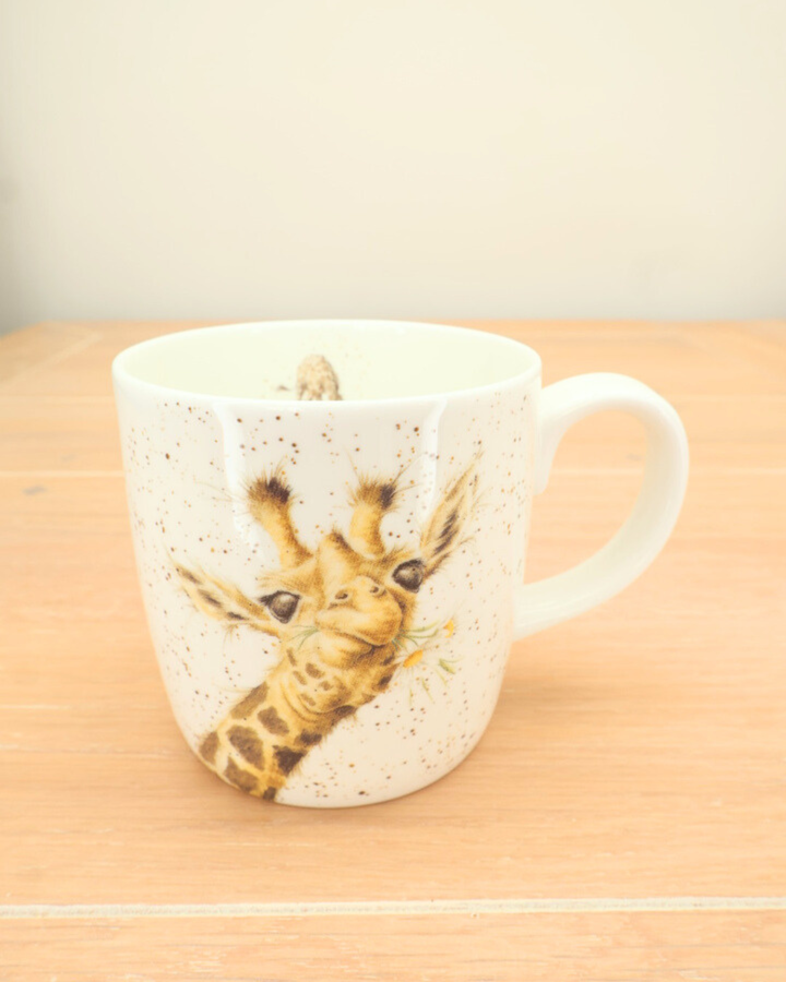 Große Giraffen-Tasse „Lofty“ auf hellem Holztisch, Detailaufnahme des Giraffenmotivs.