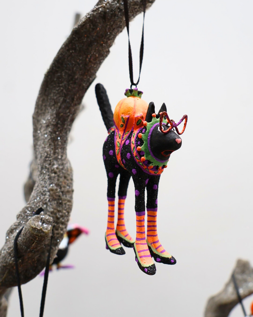 An einem Ast hängende Krinkle Katze Mini Back Cat von Patience Brewster.