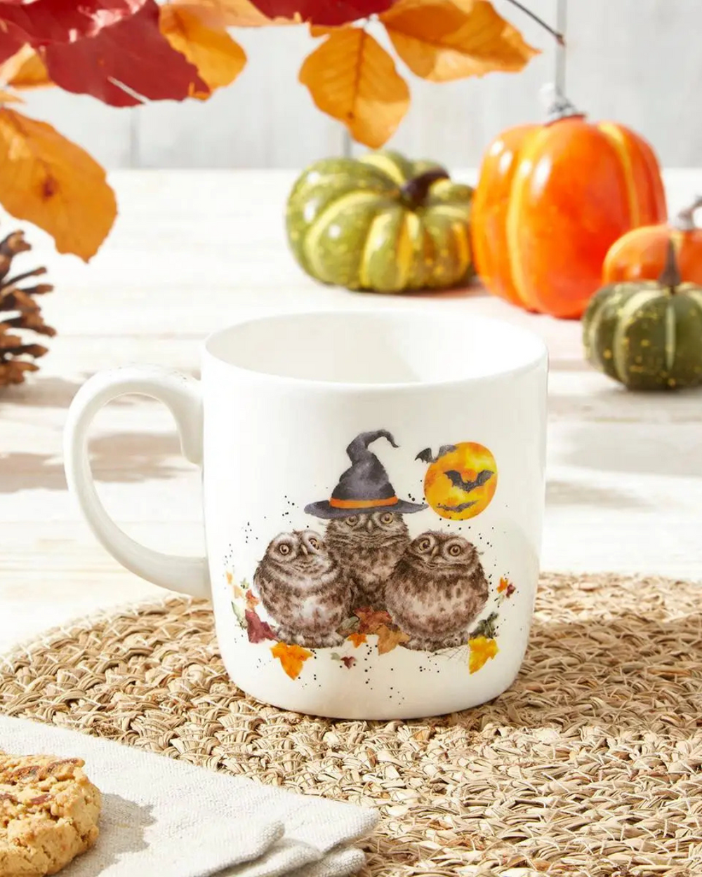 Schaurig schöne Halloween Tasse mit Eulen-Motiv von Wrendale Designs auf einem herbstlich dekorierten Tisch.