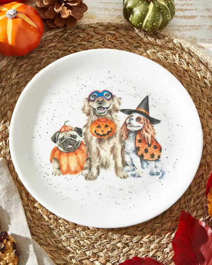Detailreicher Halloween-Teller von Wrendale Designs mit fröhlichen Hunden in Kostümen auf einem Tisch mit herbstlicher Deko.