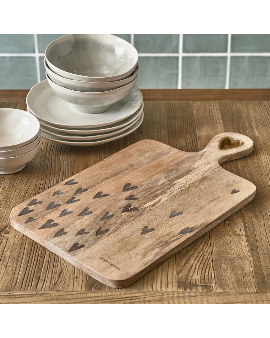Happy Hearts Chopping Board von Rivièra Maison aus Holz mit Herzmotiven auf Holztisch