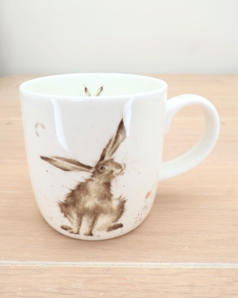 Hasen-Tasse „Hare Day“ auf hellem Holztisch, Detailaufnahme des Hasenmotivs.