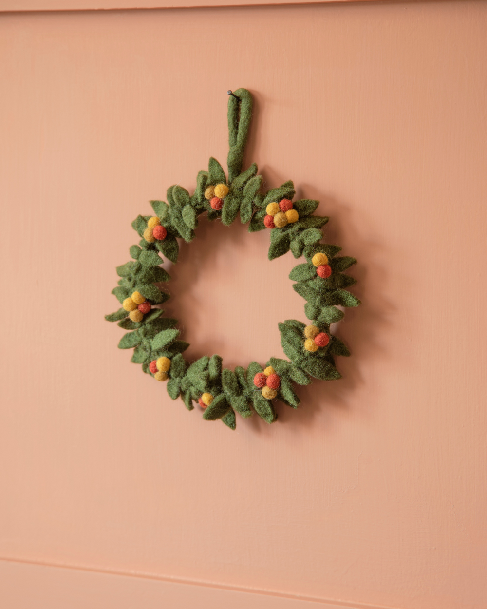Herbstkranz aus Filz von Gry & Sif an einer knallig orangenen Wand dekoriert.