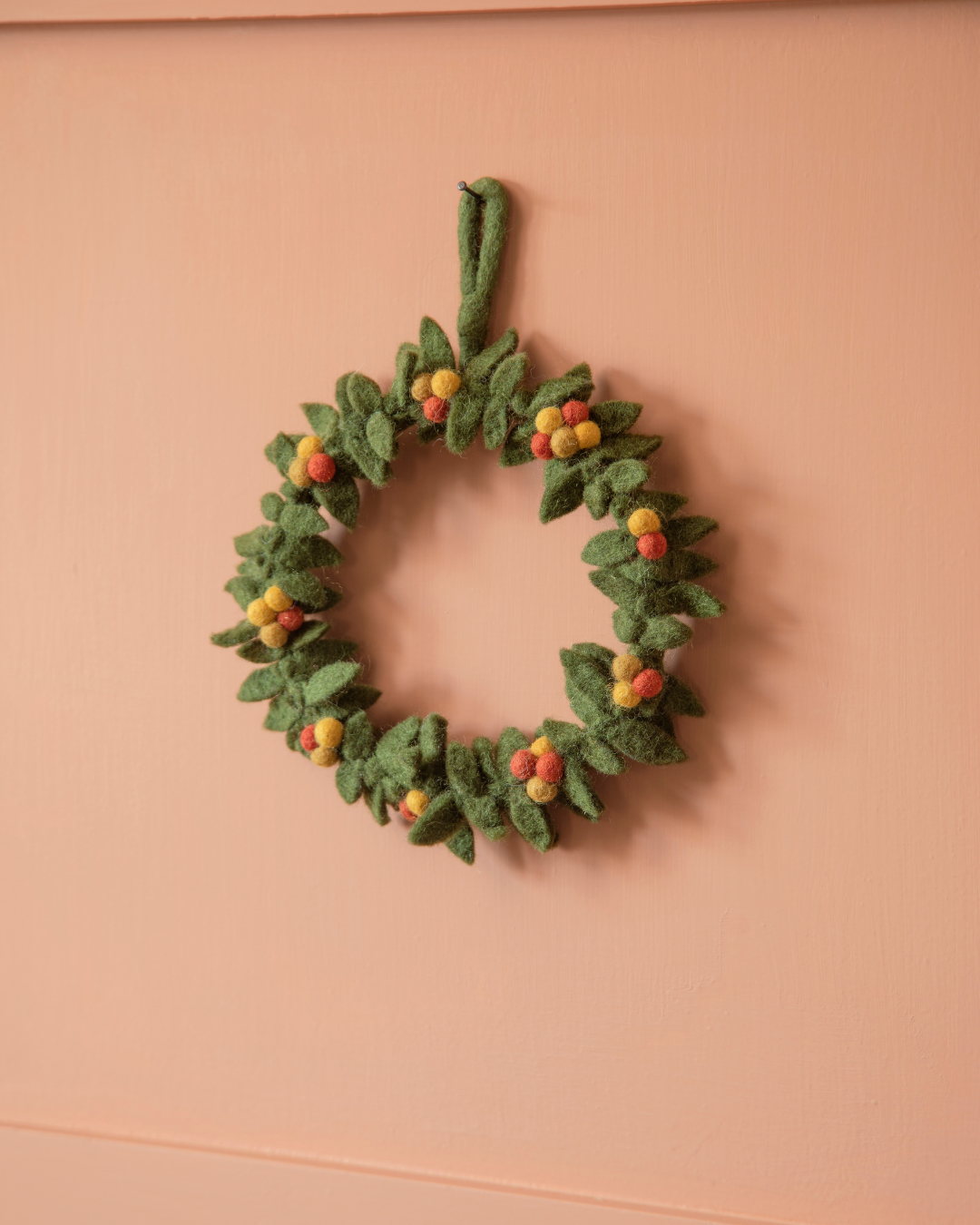 Herbstkranz aus Filz von Gry & Sif an einer knallig orangenen Wand dekoriert.
