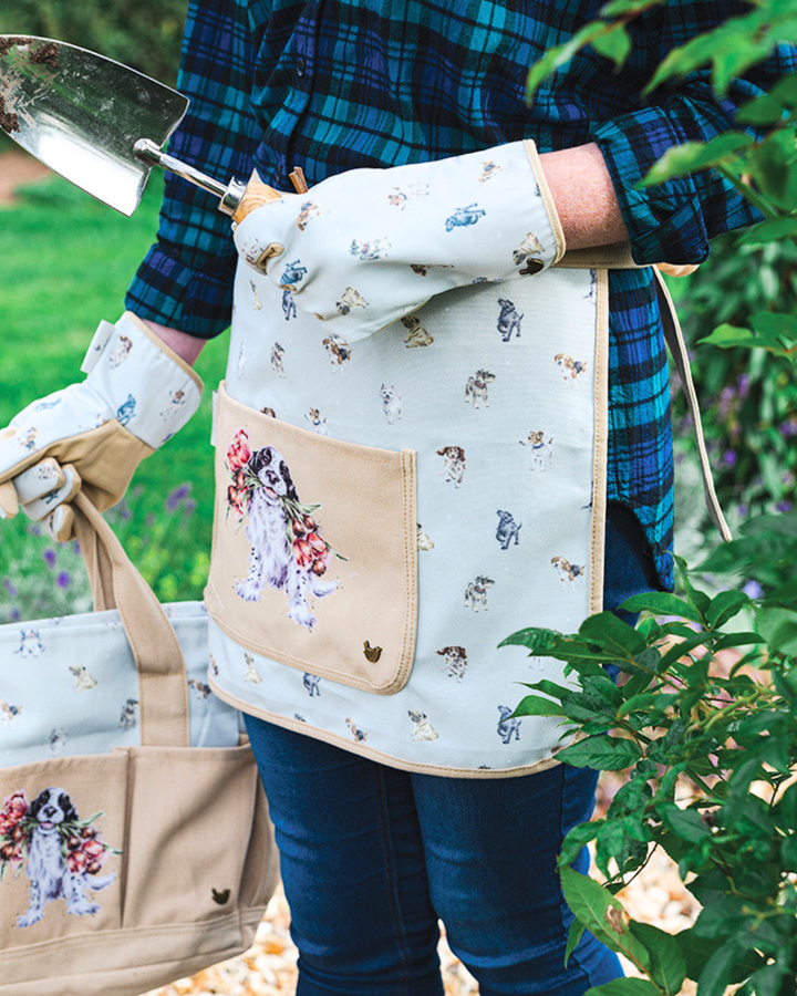 Getragene Hunde Gartenschürze "Blooming with Love" von Wrendale Designs in einem Garten.